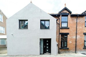 A modern two-story building with a flat roof, a black door, and a nameplate that reads 'JAMES COURT'. - James Court Llandudno Luxury Apartment 3 & Parking (Llandudno)