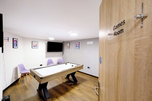 A room with a pool table, two purple chairs, a television mounted on the wall, and a door labeled 'Games Room'. - James Court Llandudno Luxury Apartment 7 & Parking (Llandudno)
