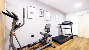 Ein Heimfitnessraum mit einem Ergometer, einem Crosstrainer und einem Laufband.