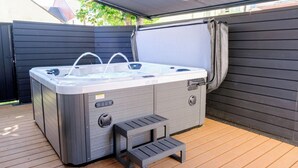 Ein Whirlpool mit Stufen, eine überdachte Terrasse und ein Holzboden.