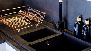 Eine Küche mit Holzausstattung, Kupferkochgeschirr, einem schwarzen Spülbecken und einem Metalldöriggerüst.