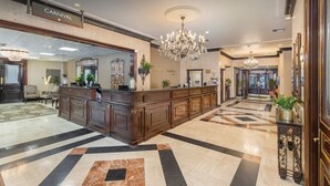 Un vestíbulo con mostrador de recepción, candelabros y suelo a cuadros.