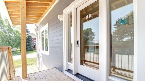 Et hus med en overdækket veranda, en skydedør med nummer 171, og udsigt til gaden.