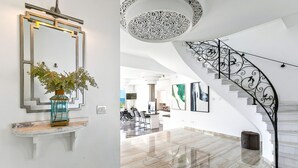 A modern interior with a marble staircase, a large mirror, and a vase with greenery.