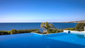 A clear blue sky, a swimming pool, and a view of the sea.