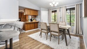 A modern kitchen with wooden cabinets, a dining area with a table and chairs, and a large window with curtains. - Two Living Spaces • Private Downstairs Suite (Grants Pass)