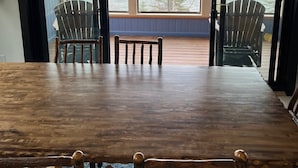 A wooden dining table with four chairs, a bench, and a view of the ocean through large windows. - Halsnoy Haven New Listing. Iconic property! (Tofte)