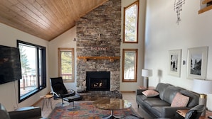 A spacious living room with a stone fireplace, leather furniture, and large windows. - Halsnoy Haven New Listing. Iconic property! (Tofte)