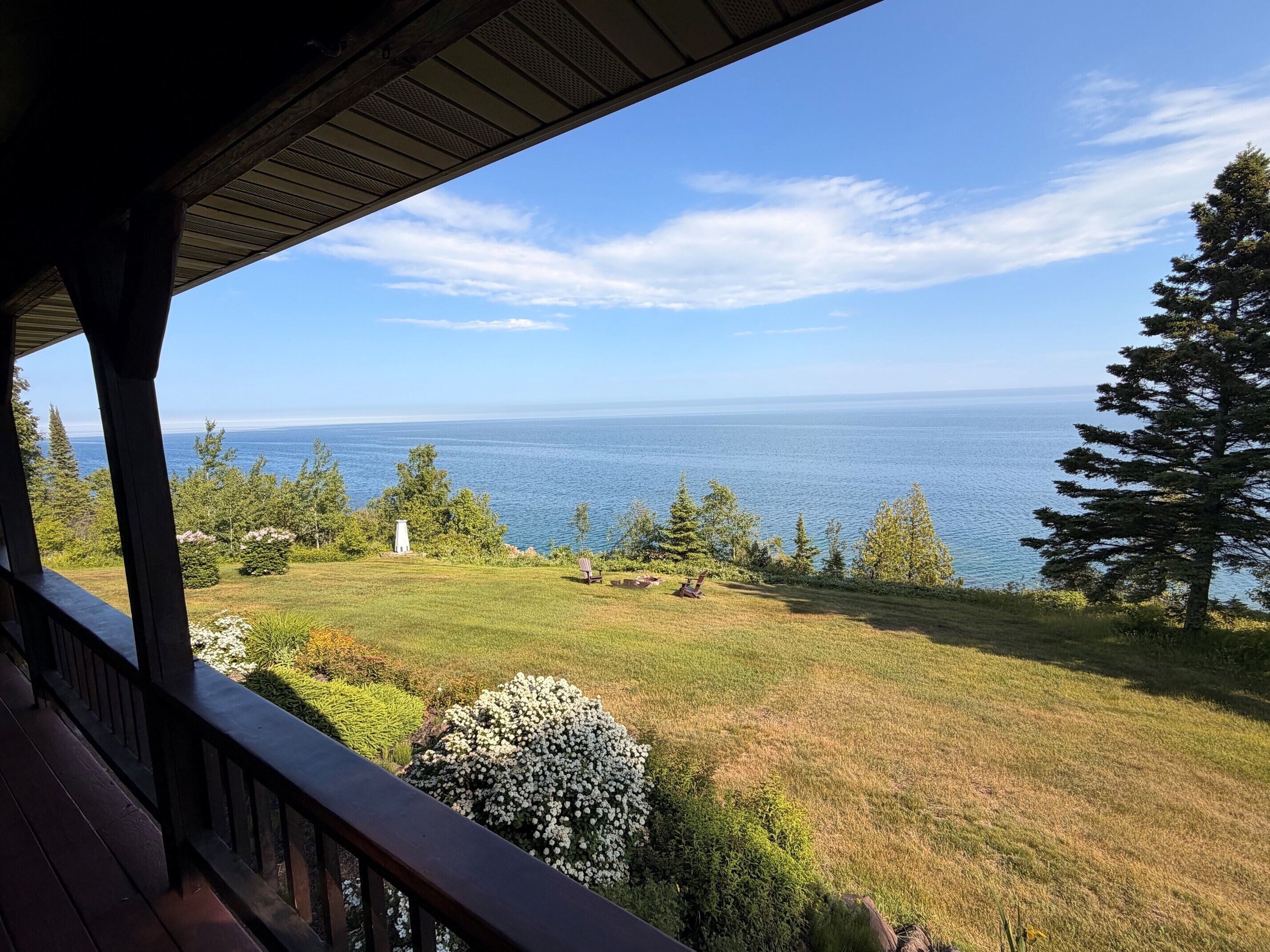 A view from a covered porch overlooking a grassy area with a body of water in the distance.