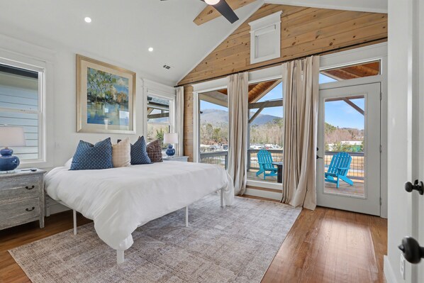 Une chambre avec un grand lit, une vue sur l’extérieur et un balcon avec une chaise.