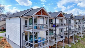 A multi-story residential building with a balcony on each floor, featuring outdoor seating and a view of the surrounding area. - Modern & Stylish 2/2.5 Home Mainstreet Clayton! (Clayton)