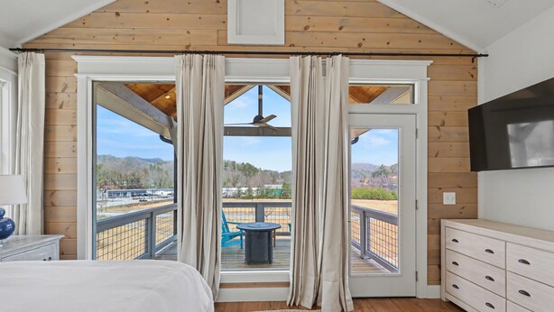 A bedroom with a large window, wooden ceiling, and a TV on the wall. - Modern & Stylish 2/2.5 Home Mainstreet Clayton! (Clayton)