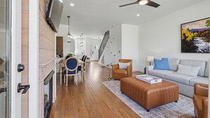 A modern living room with a fireplace, a sofa, a coffee table, and a dining area with chairs and a table. - Modern & Stylish 2/2.5 Home Mainstreet Clayton! (Clayton)