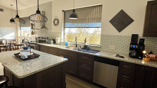 Una cocina moderna con encimeras de granito, armarios oscuros e iluminación colgante.