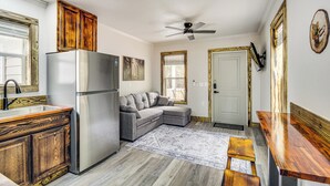 A compact kitchen with a refrigerator, a wooden cabinet, a gray sofa, and a dining table. - Explore, Shop & Unwind: Serene Gulfport Getaway (Gulfport)