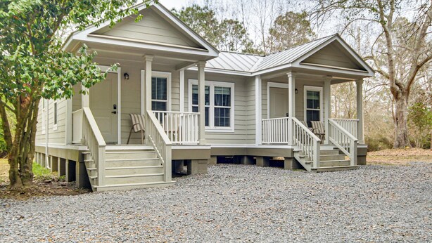 A two-story house with a covered porch and a gravel driveway. - Explore, Shop & Unwind: Serene Gulfport Getaway (Gulfport)