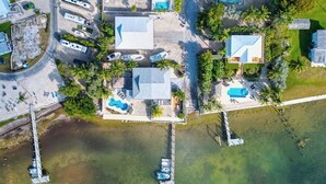 An aerial view of a coastal property with multiple buildings, a swimming pool, and a dock with boats.