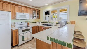 A kitchen with wooden cabinets, a microwave, a stove, a sink, and a window with a view.