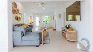Una sala moderna con un sofá gris, una mesa de centro y un comedor con una silla blanca.