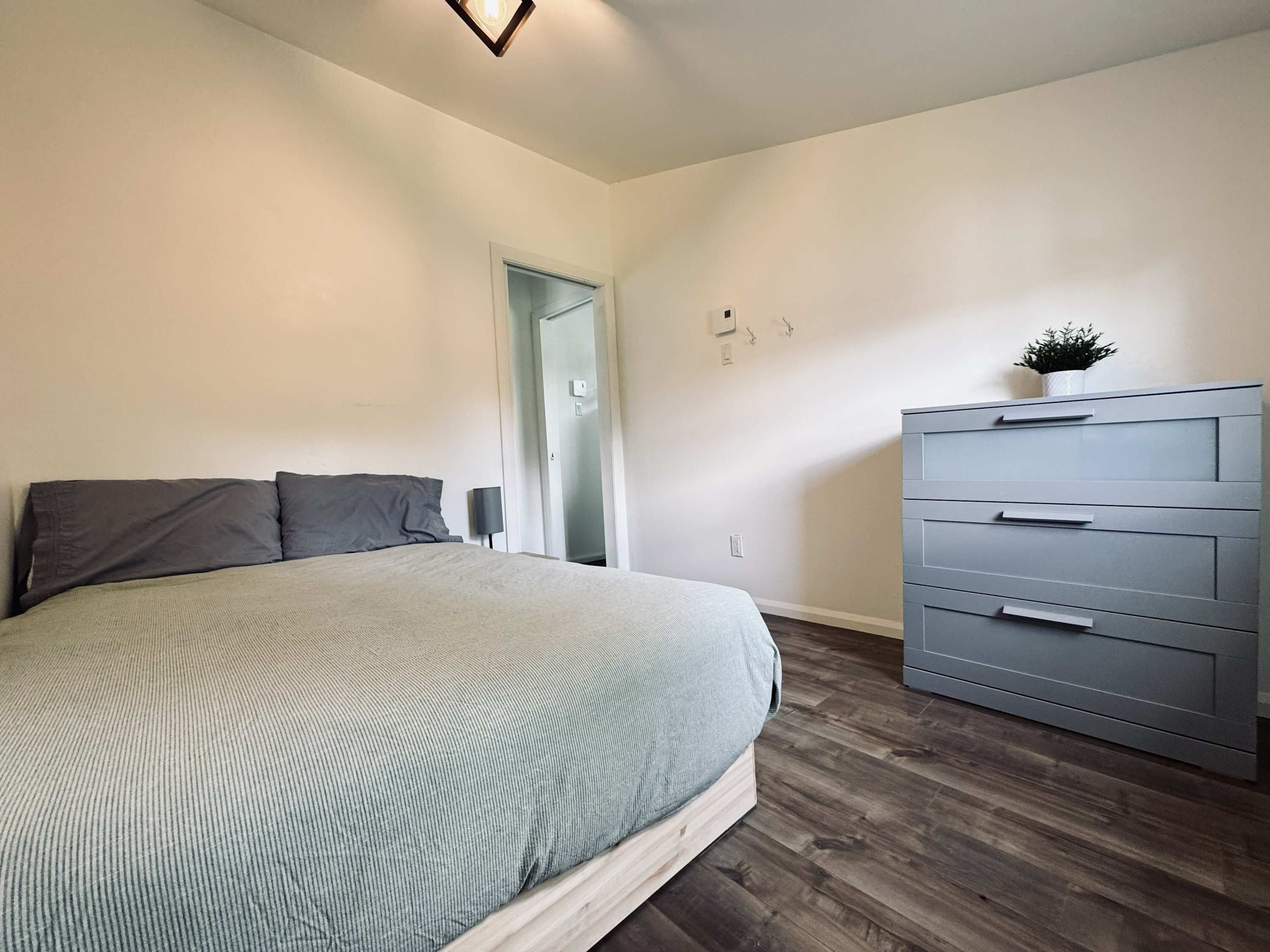 Une chambre à coucher comprenant un lit, une commode et une porte donnant sur une autre pièce.