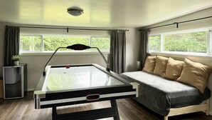 Une pièce avec une table de billard, un canapé et de grandes fenêtres.