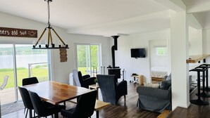 Un salon moderne avec une table à manger en bois, des chaises noires, un canapé gris et une cheminée noire.