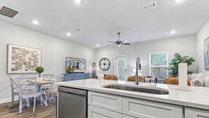 A modern kitchen with white cabinetry, a built-in dishwasher, and a central island with a sink. - Brand-new Coastal Escape 3BR/2.5BA minutes from vibrant downtown Ocean Springs. (Ocean Springs)