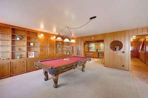 Una mesa de billar en una habitación con paneles de madera y estanterías.