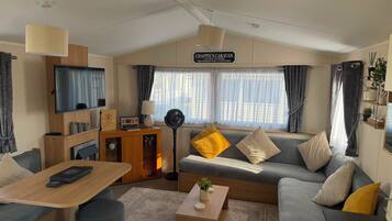 Een moderne woonkamer met een bank, salontafel, televisie en een bord boven de bank.