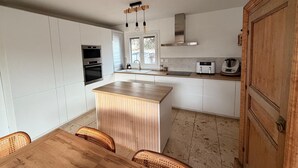 A modern kitchen with white cabinets, a wooden island, and a built-in oven. - Family villa in the heart of the Vaucluse (Sorgues)