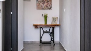 En hall med ett konsolbord i trä, en vas med gröna växter, en inramad motiverande citat och en gammal symaskin.