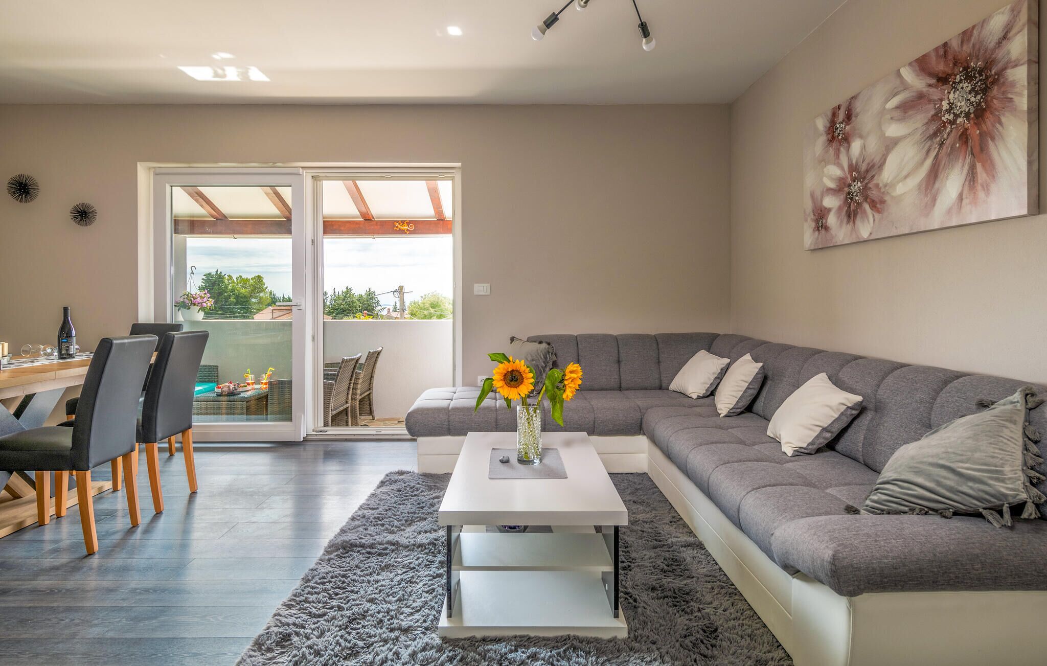 Un salon moderne avec un canapé gris, une table basse blanche et un coin repas comprenant des chaises et une table.
