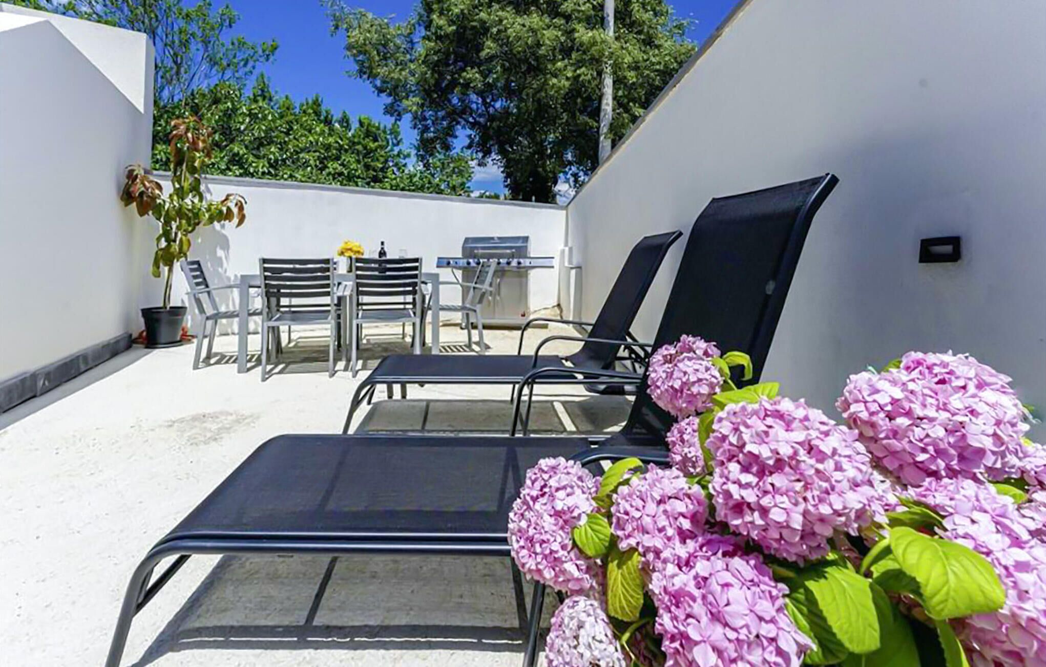 Eine Terrasse mit Lounge-Möbeln, einem Tisch und einem Grill.