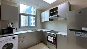 Ett kompakt kök med tvättmaskin, mikrovågsugn, spis och kylskåp.