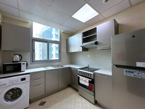 Eine kleine Küche mit Waschmaschine, Mikrowelle, Herd und Kühlschrank.