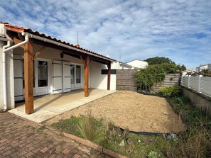 A house with a covered patio, a fenced yard, and a wooden fence.