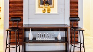A modern interior with a wooden wall, a framed picture, and a 'HOME' sign on a table. - The Cabin – 3BR Log Retreat w/Outdoor Bar & Grill (Jupiter)