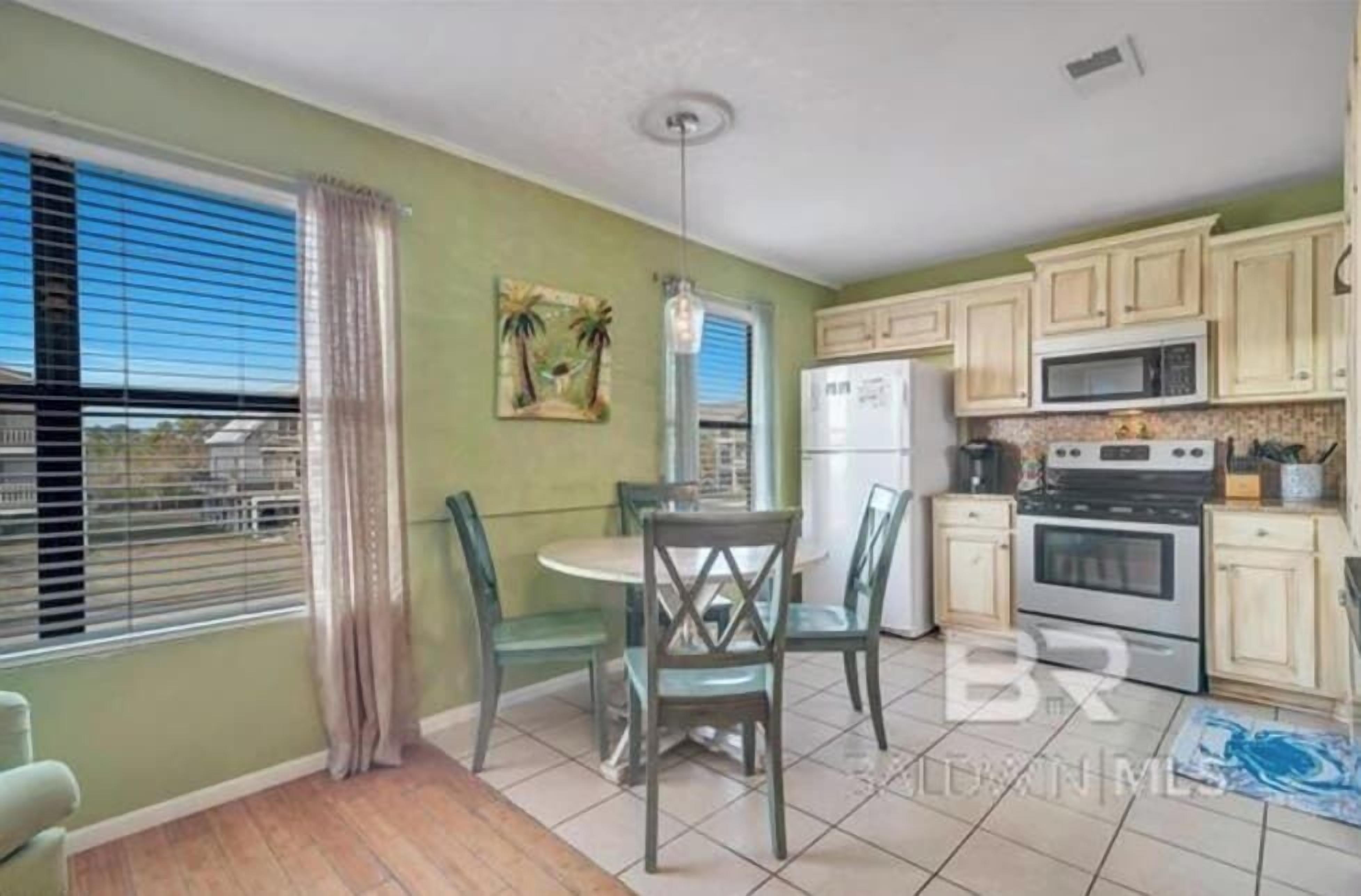 A compact kitchen with a dining area, featuring a refrigerator, microwave, stove, and a dining table with chairs.