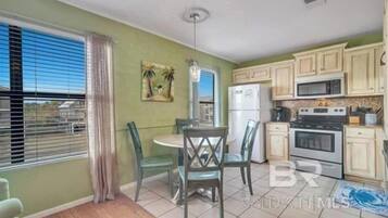 A compact kitchen with a dining area, featuring a refrigerator, microwave, stove, and a dining table with chairs.
