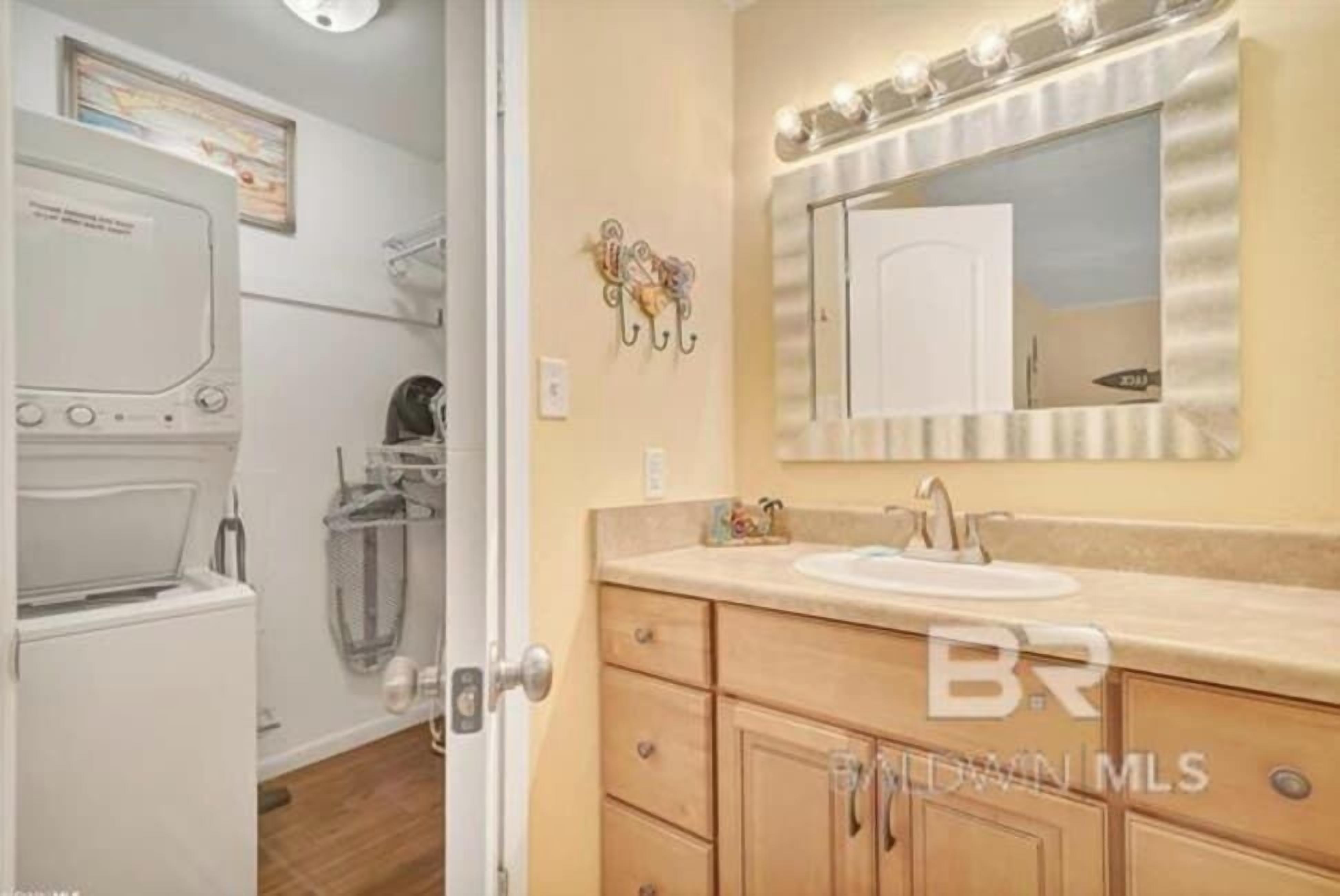 A bathroom with a sink, mirror, and a washing machine.