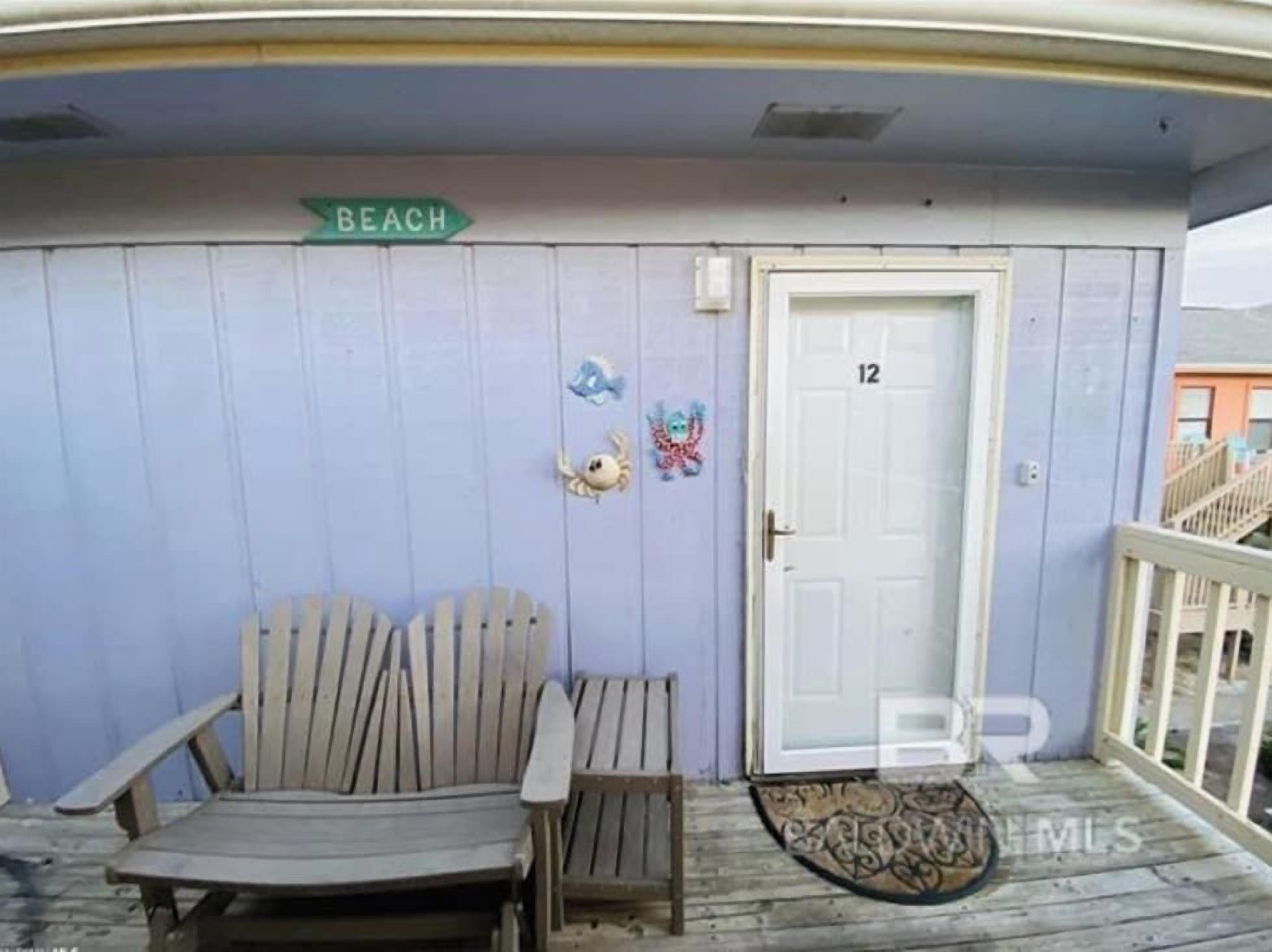 Una habitación con un banco de madera, una puerta marcada con el número 12 y un letrero que dice 'BEACH'.