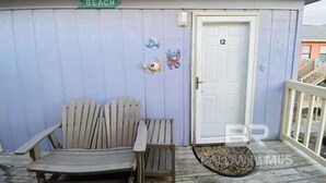 A room with a wooden bench, a door marked with the number 12, and a 'BEACH' sign above. - Pet Friendly Beach Access Sleeps 6 Hangout Nearby (Gulf Shores)