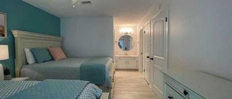 Een slaapkamer met twee bedden, een plafondventilator, een spiegel en een inloopkast.
