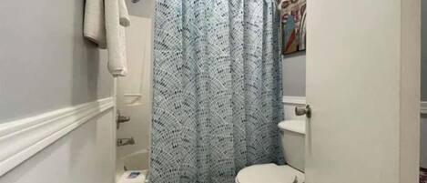 Een kleine badkamer met een wit toilet, een blauw douchegordijn en een handdoek aan een rek.