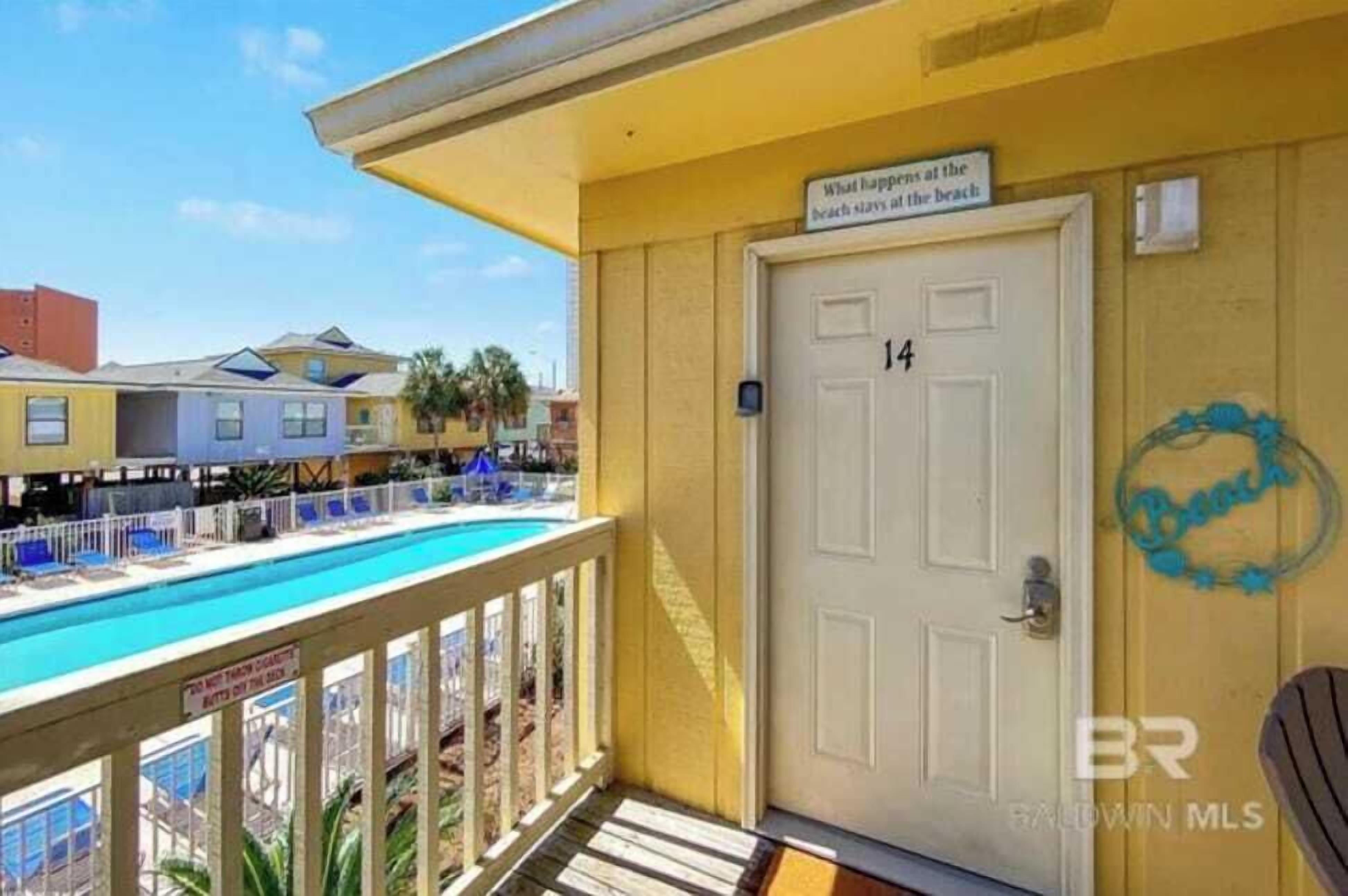 A yellow building with a pool and a door marked "14".