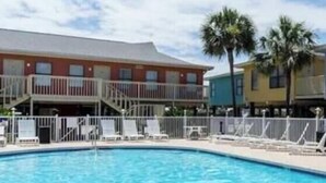 A swimming pool with lounge chairs and a building with balconies in the background. - Pet Friendly Beach Access Hangout Nearby Sleeps 6 (Gulf Shores)