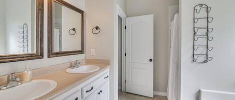Une salle de bain avec deux lavabos, un grand miroir et une douche.