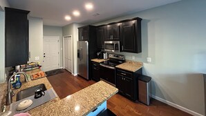 A modern kitchen with dark cabinetry, granite countertops, stainless steel appliances, and a built-in microwave. - Master’s Rental - 2 weeks 3 bed/2bath - 3 miles from golf course Augusta, GA (Augusta)