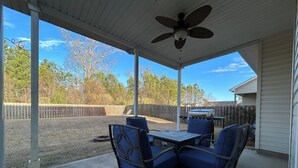 A covered patio with a table and chairs, a ceiling fan, and a view of a backyard with a grill and a wooden fence. - Master’s Rental - 2 weeks 3 bed/2bath - 3 miles from golf course Augusta, GA (Augusta)