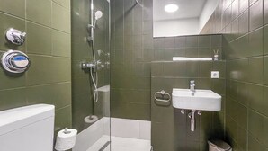 Une salle de bain équipée d’une douche, de toilettes, d’un lavabo et d’une poubelle.